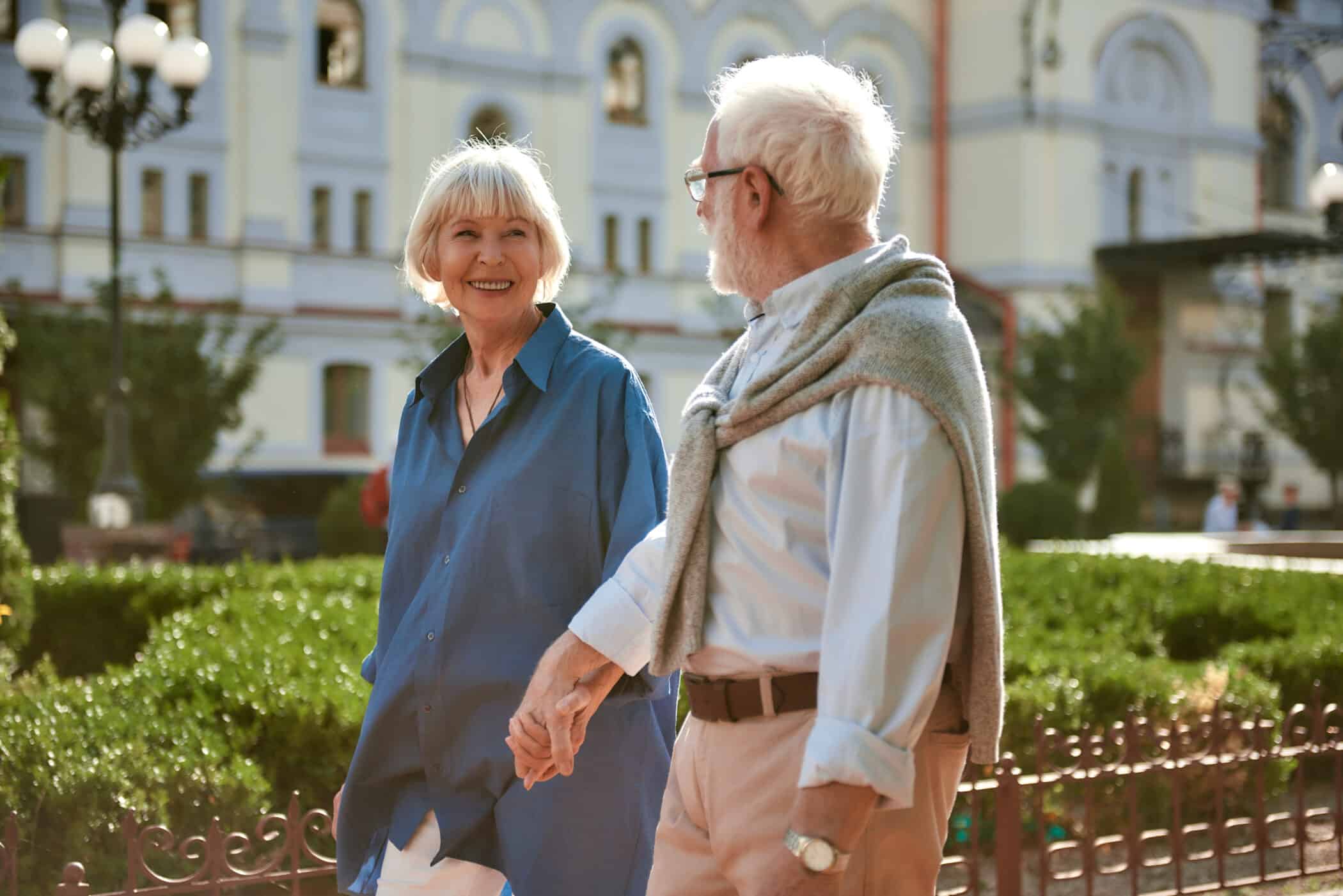 I love my husband. Happy and beautiful elderly couple holding hands and looking at each other while walking outdoors